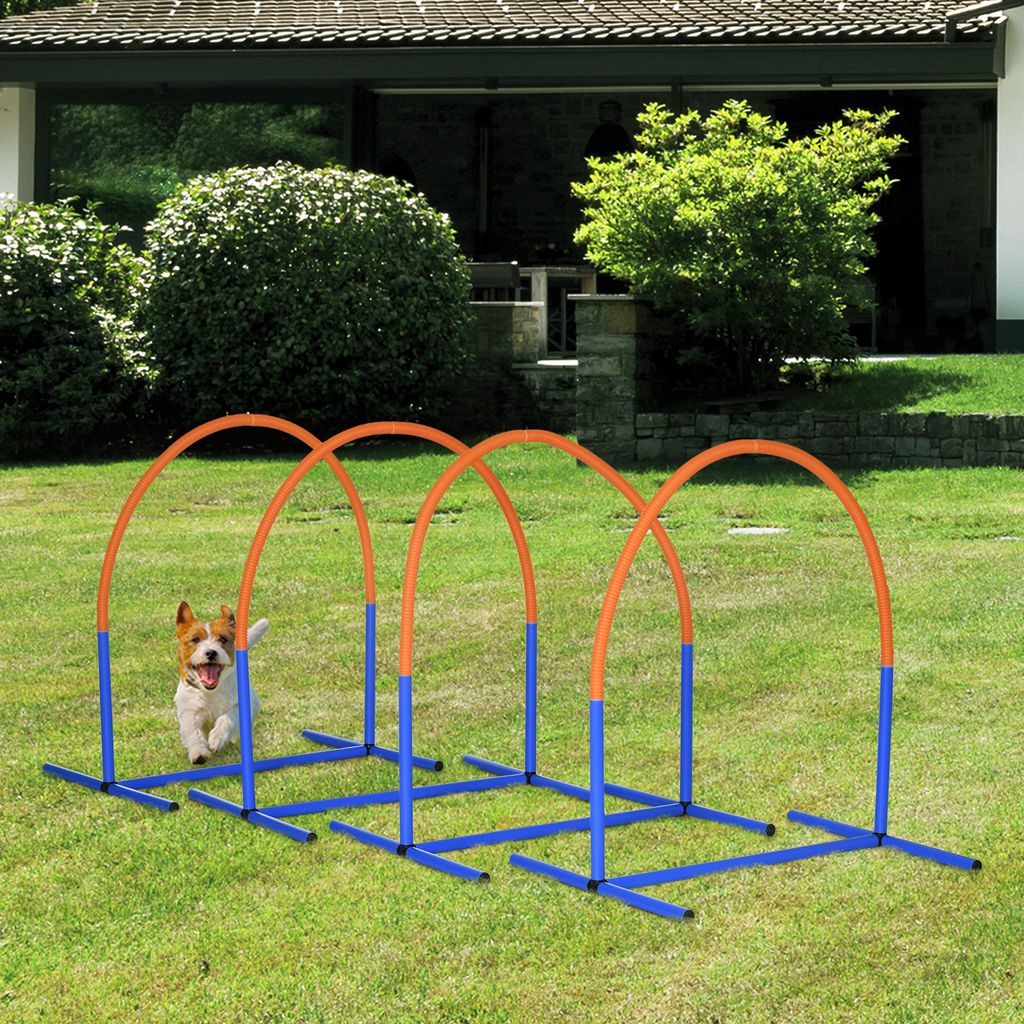 A dog is running through agility hoops in a backyard.