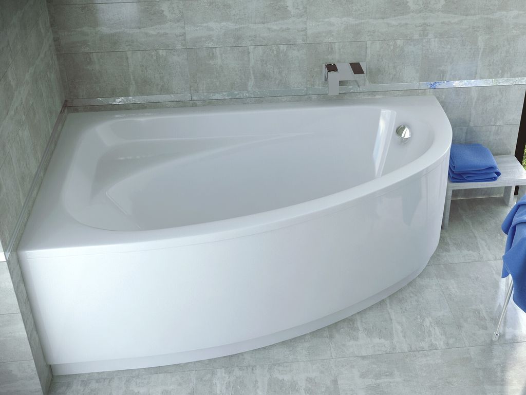 A white corner bathtub with a curved front panel, set against a tiled wall and floor.