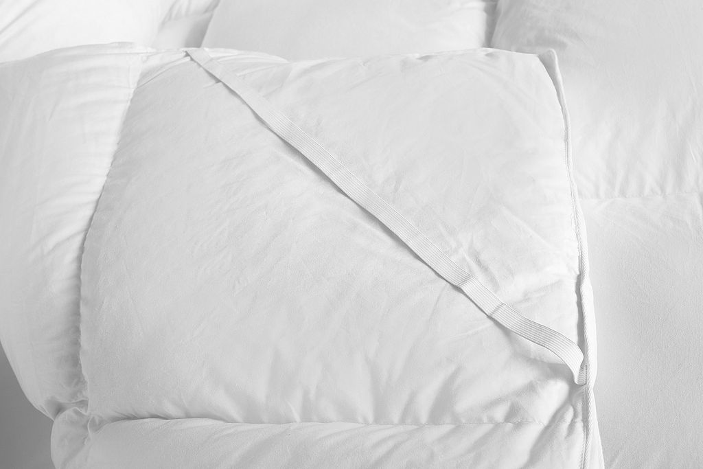 A close-up view of a white duvet or mattress topper with a fabric tie.
