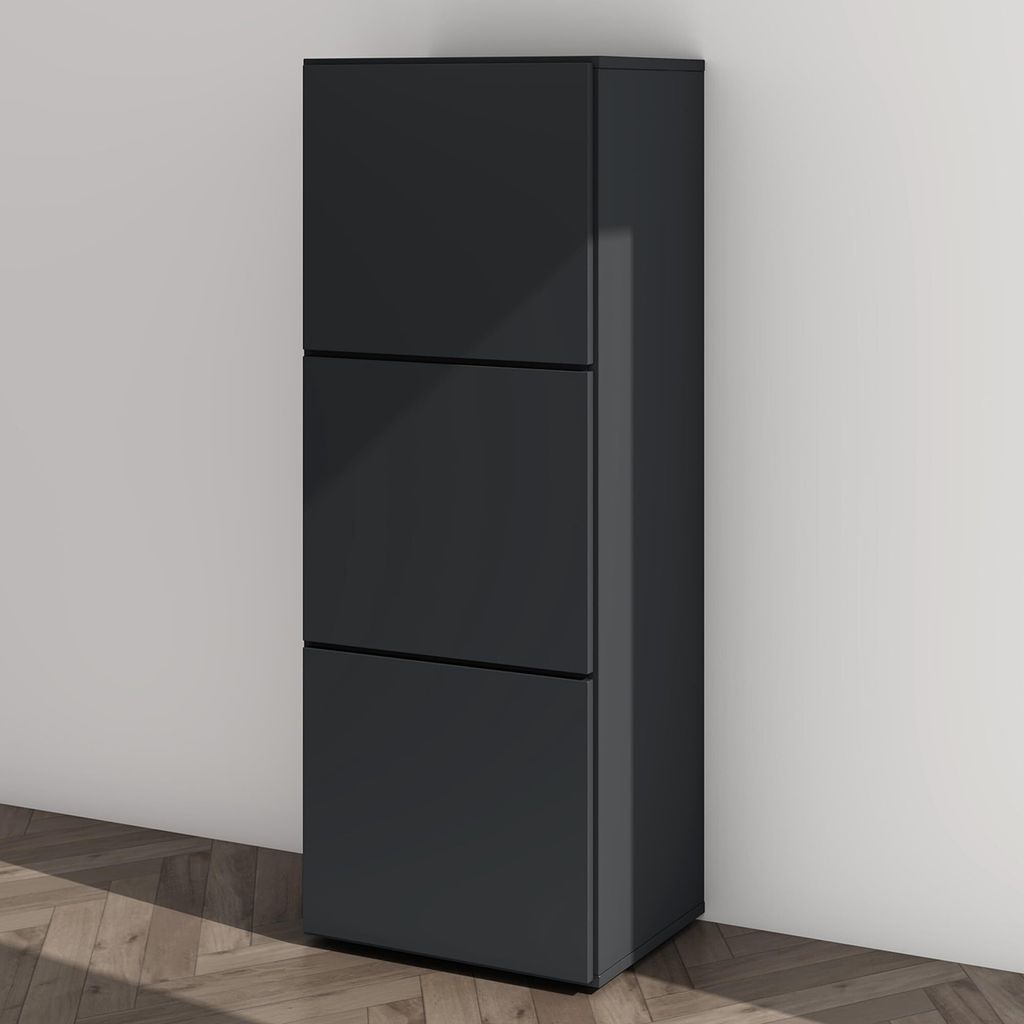 A dark gray shoe cabinet with three drawers stands against a light gray wall, with a wooden floor in the foreground.