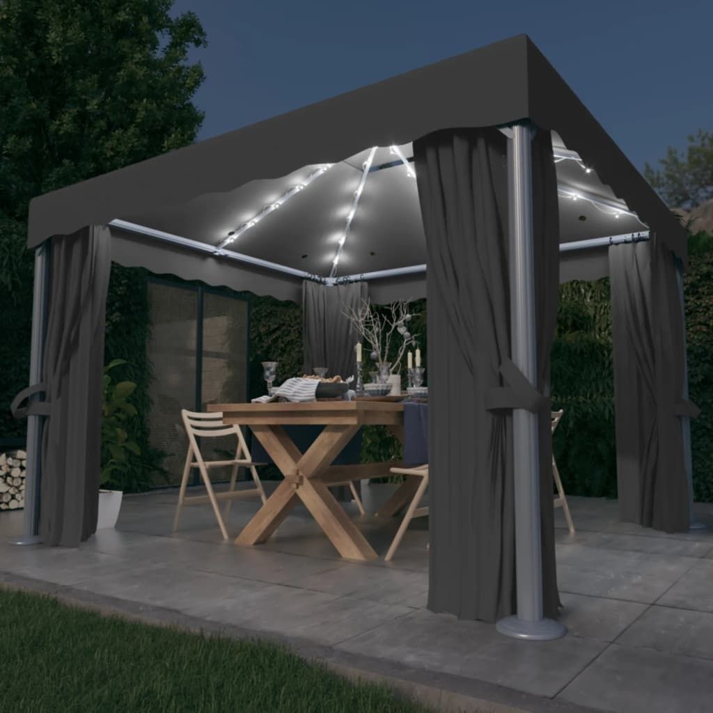 An outdoor pavilion set up for dining at night, with lights and curtains.