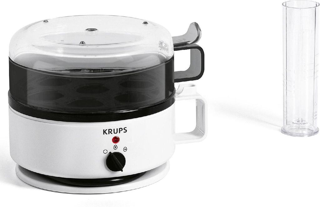 A white Krups egg cooker with a clear lid and a measuring cup next to it, on a white background.
