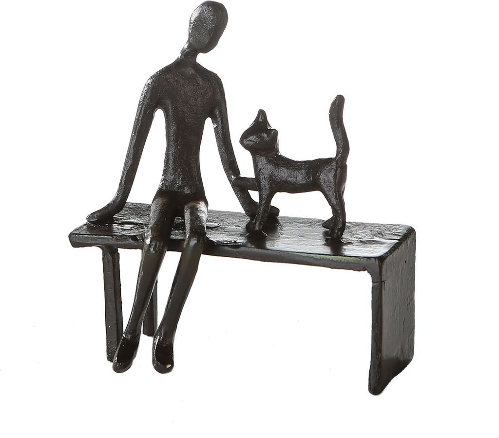 A dark, stylized sculpture of a person sitting on a bench with a cat standing next to them.