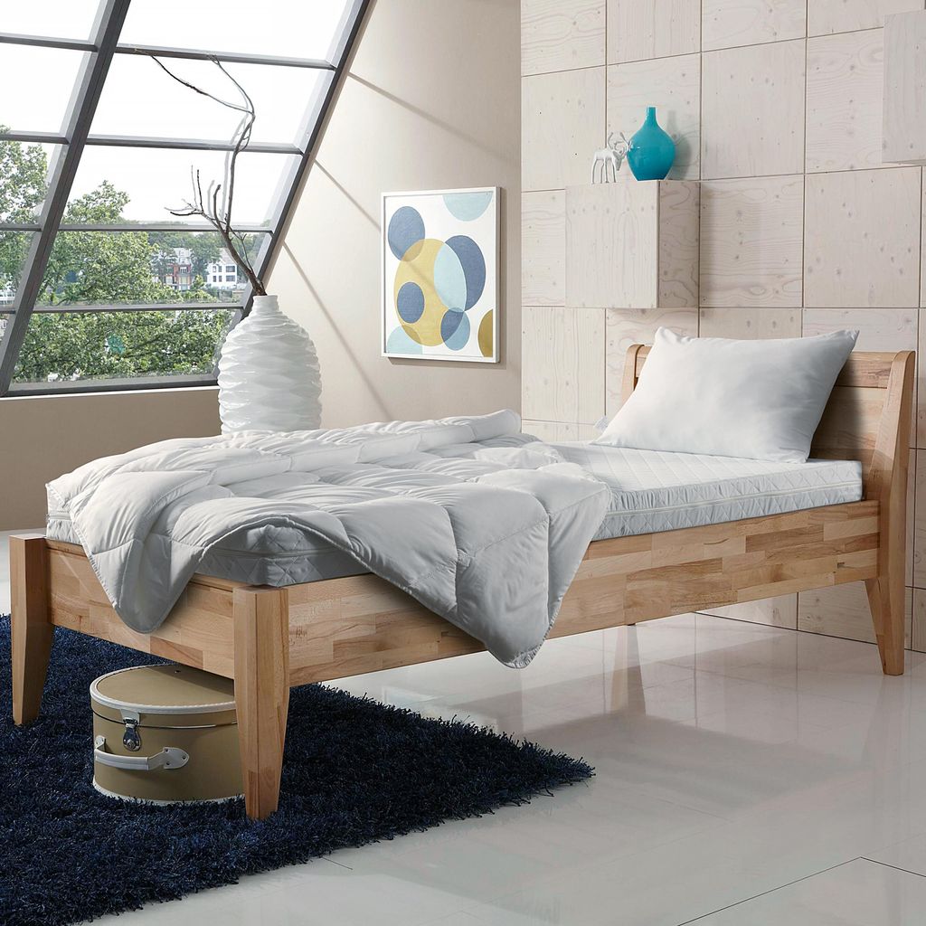 A bedroom scene with a bed, bedding, and decorative items.