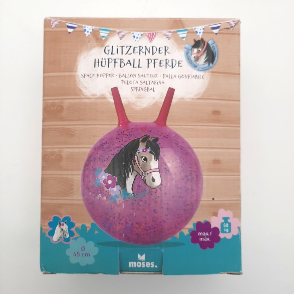 The image shows the packaging of a glittery horse-themed hopper ball. The packaging features a wooden plank background and a drawing of the hopper ball with a horse illustration on it.