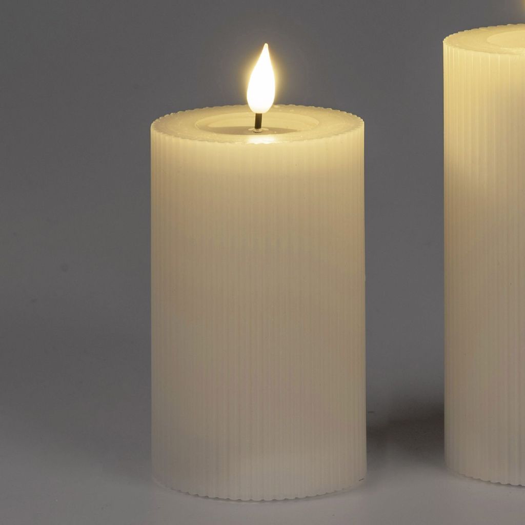 A close-up of a cream-colored LED candle with a flame.
