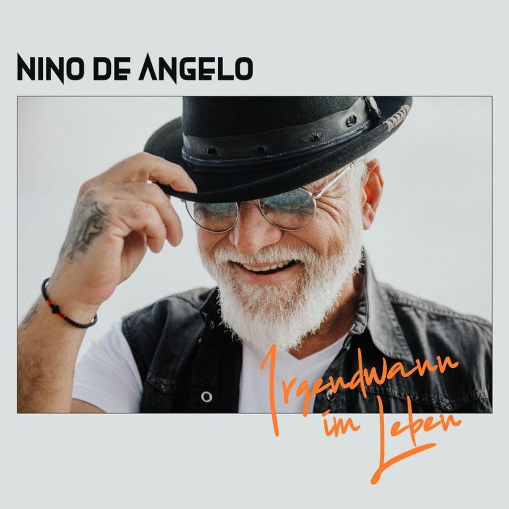 A man wearing a hat and sunglasses, smiling.