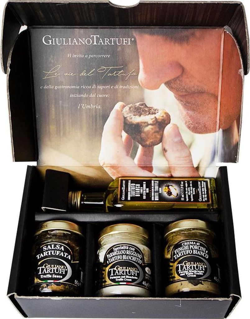 A gift set of truffle products, including jars of sauce and cream, and a bottle of oil, presented in an open box with marketing imagery on the lid.