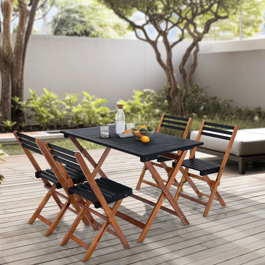 An outdoor patio scene with a wooden table and chairs set up on a wooden deck, surrounded by greenery and a wall.