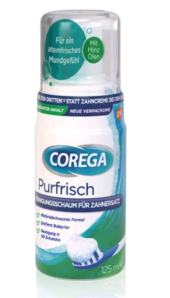 A bottle of Corega Purfrisch cleaning foam for dentures, shown with a toothbrush and foam.