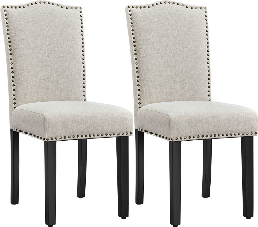 Two beige upholstered dining chairs with black legs and nailhead trim, presented against a white background.