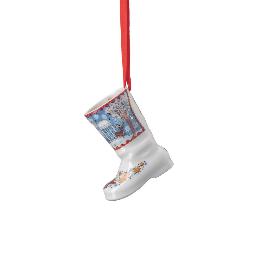 A white ceramic Christmas boot ornament with a winter scene depicted on it, hanging from a red ribbon.
