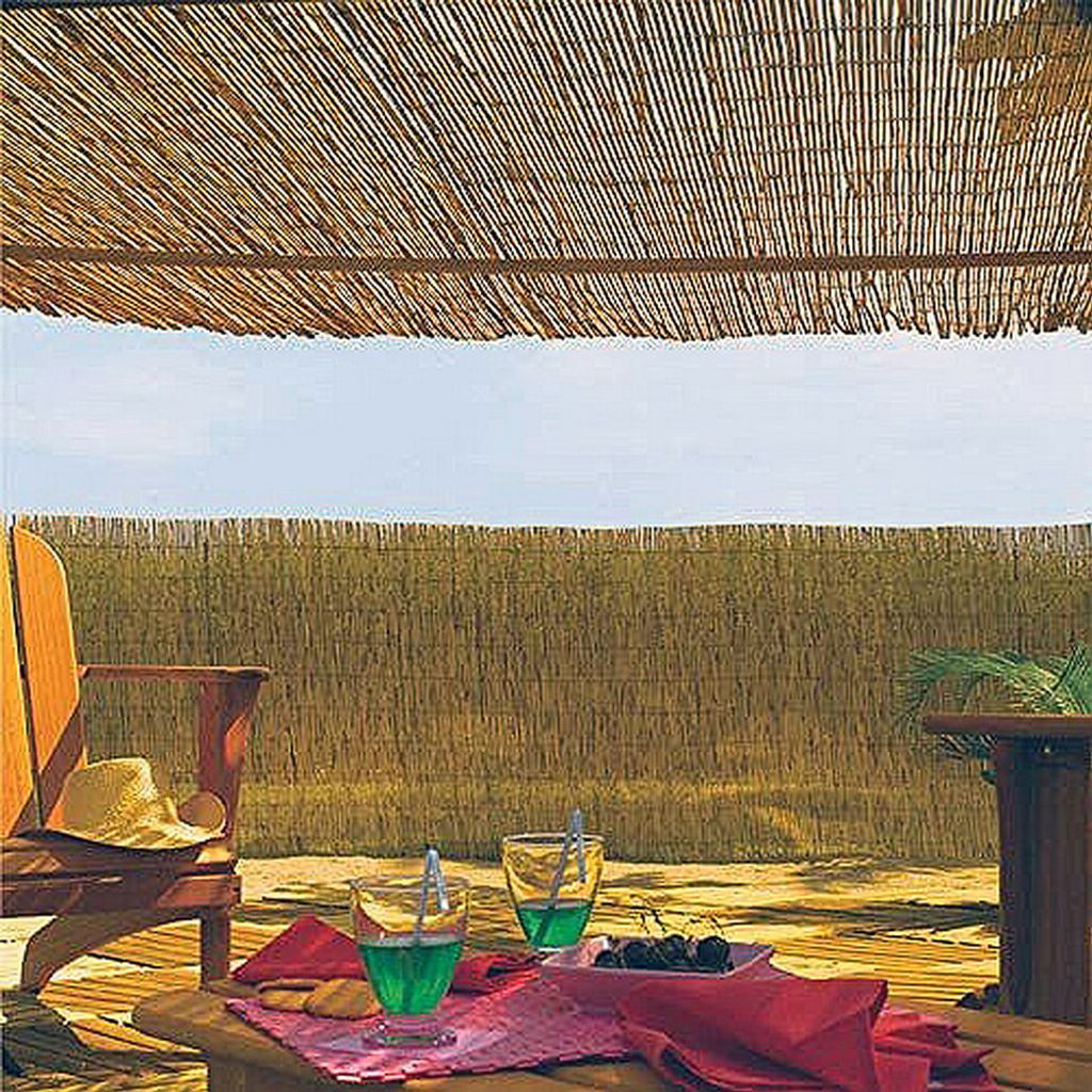 A relaxed outdoor setting with drinks and a hat on a chair, under a bamboo canopy.