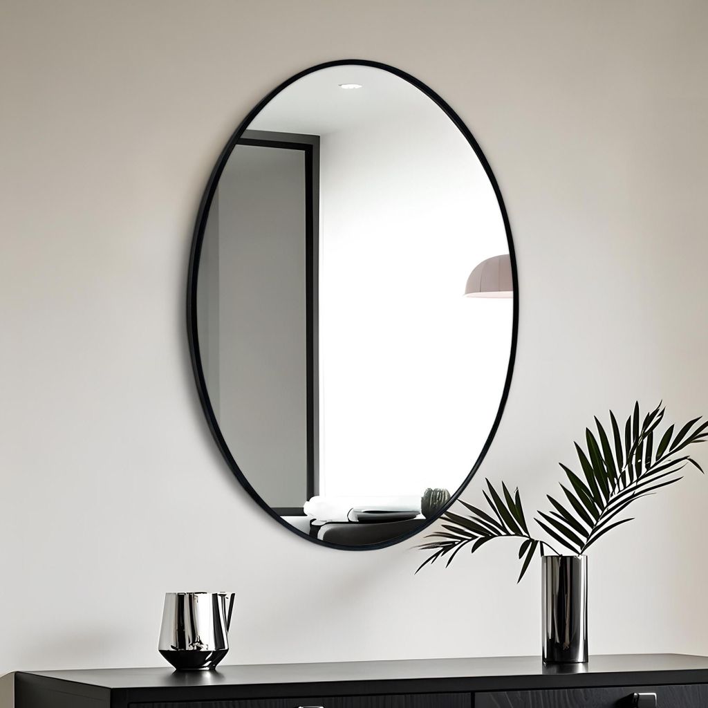 A modern interior scene featuring an oval mirror on a wall above a dark dresser.