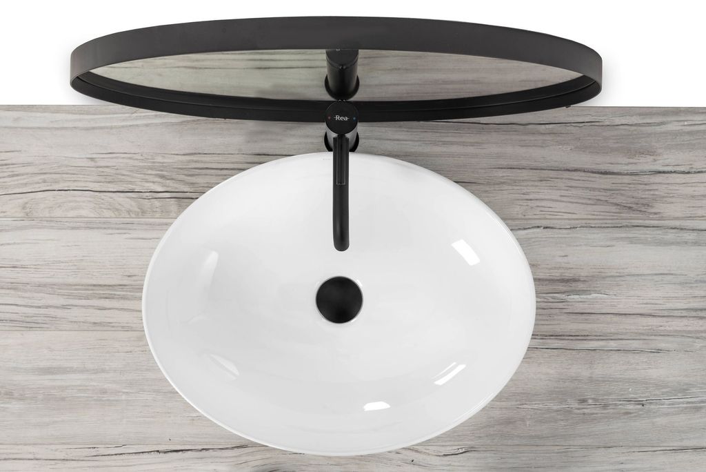 A white oval basin sink with a black faucet and drain, mounted on a wooden surface.