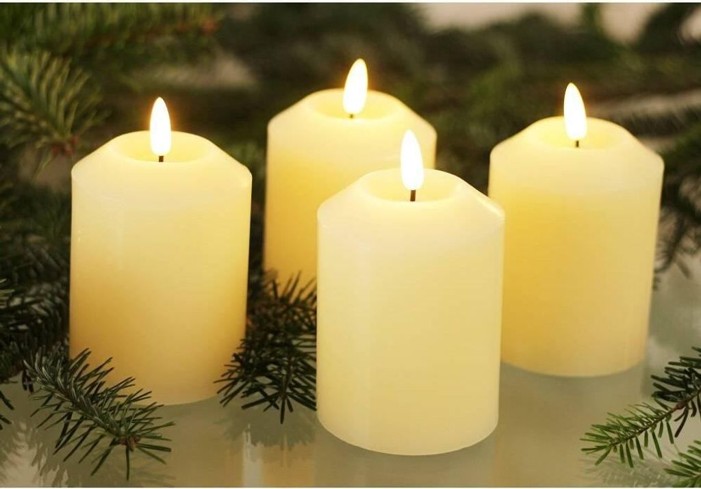 Four cream-colored LED candles are arranged with pine branches in the foreground and background.