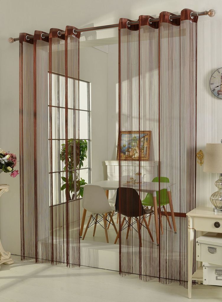 A dining area with chairs and a table, partially obscured by string curtains.