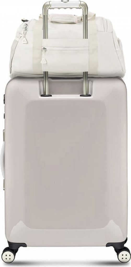 A light-colored duffel bag is placed on top of a light-colored suitcase.
