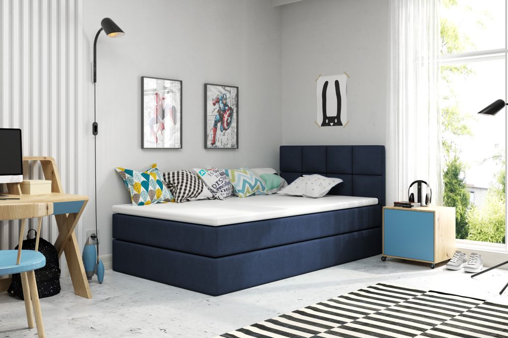 A bedroom with a blue bed, desk, and colorful pillows.