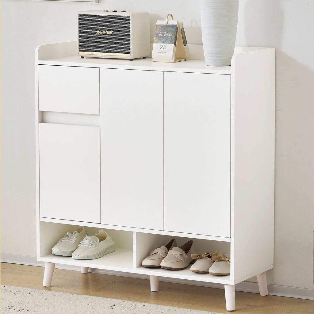 A white shoe cabinet with a drawer and three doors, standing on wooden legs.