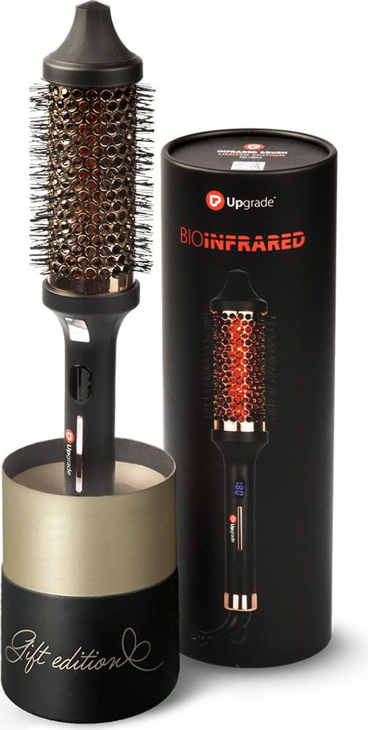 A round hairbrush and its cylindrical packaging are displayed against a white background. The packaging is black with gold accents and text. The brush is black with a copper-colored barrel and bristles.