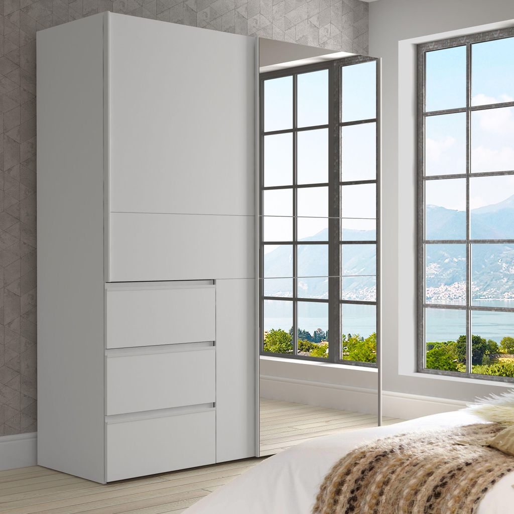 A modern bedroom with a large wardrobe featuring mirrored doors, reflecting a scenic view through large windows.