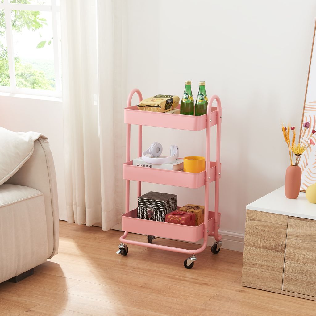 A pink three-tiered rolling cart filled with various items, placed in a room next to a sofa and a cabinet.