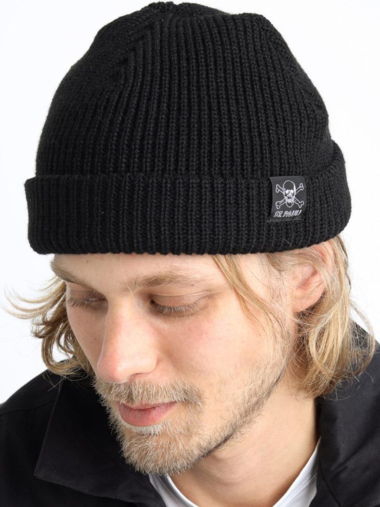 A man wearing a black beanie with a skull and crossbones logo.