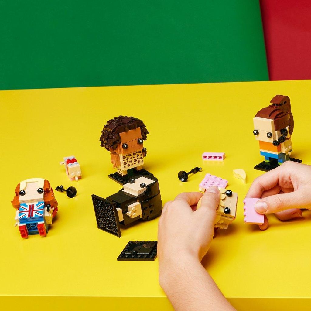 LEGO BrickHeadz figures are arranged on a yellow surface with a green and red background.