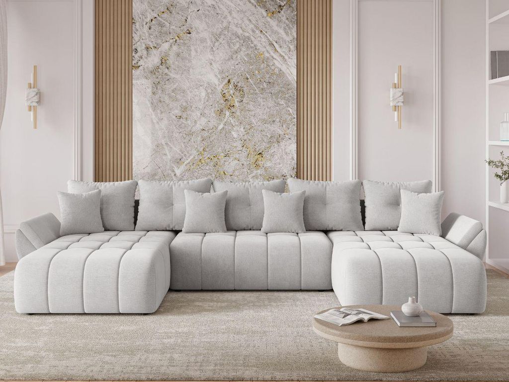 A modern, light gray U-shaped sectional sofa is arranged in a living room setting, facing a coffee table. The sofa is adorned with several matching throw pillows. Behind the sofa, a large abstract artwork with marble-like textures is displayed on a wall wi