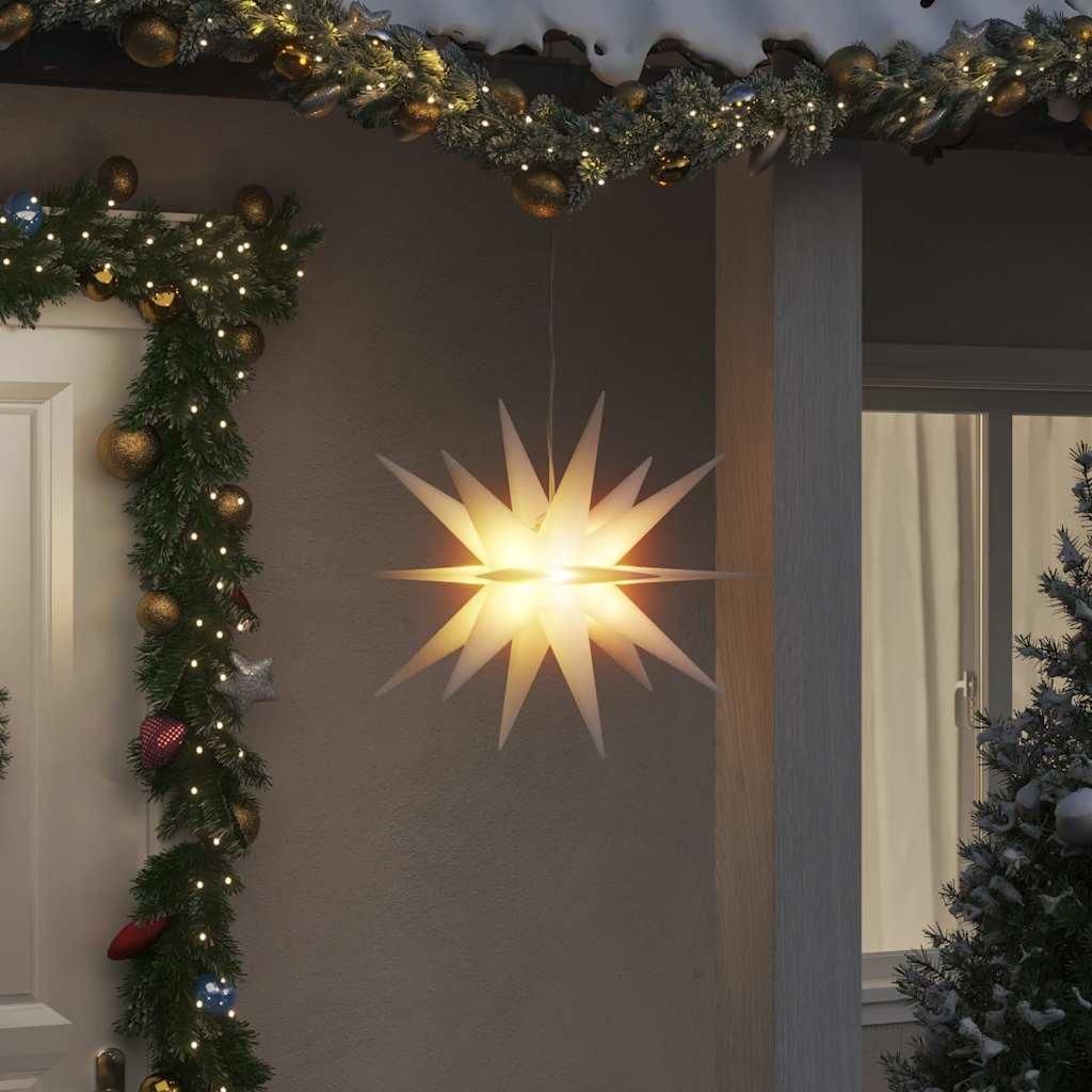 A white star-shaped LED Christmas decoration hangs outside a house, adorned with Christmas garlands and lights.