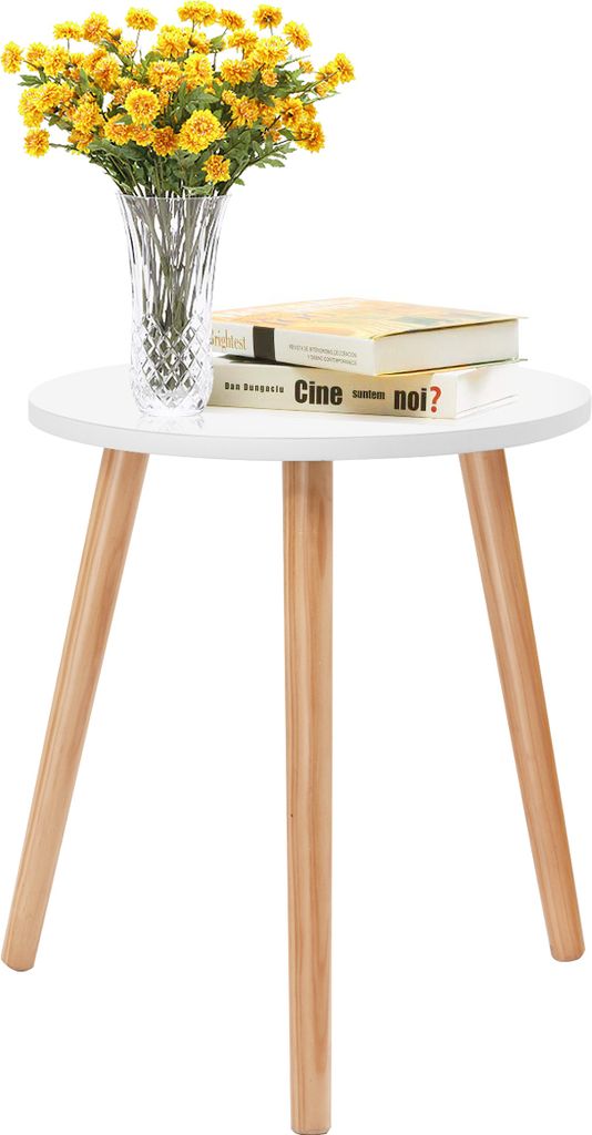 A small round white table with three wooden legs, on which a vase of yellow flowers and two books are placed.