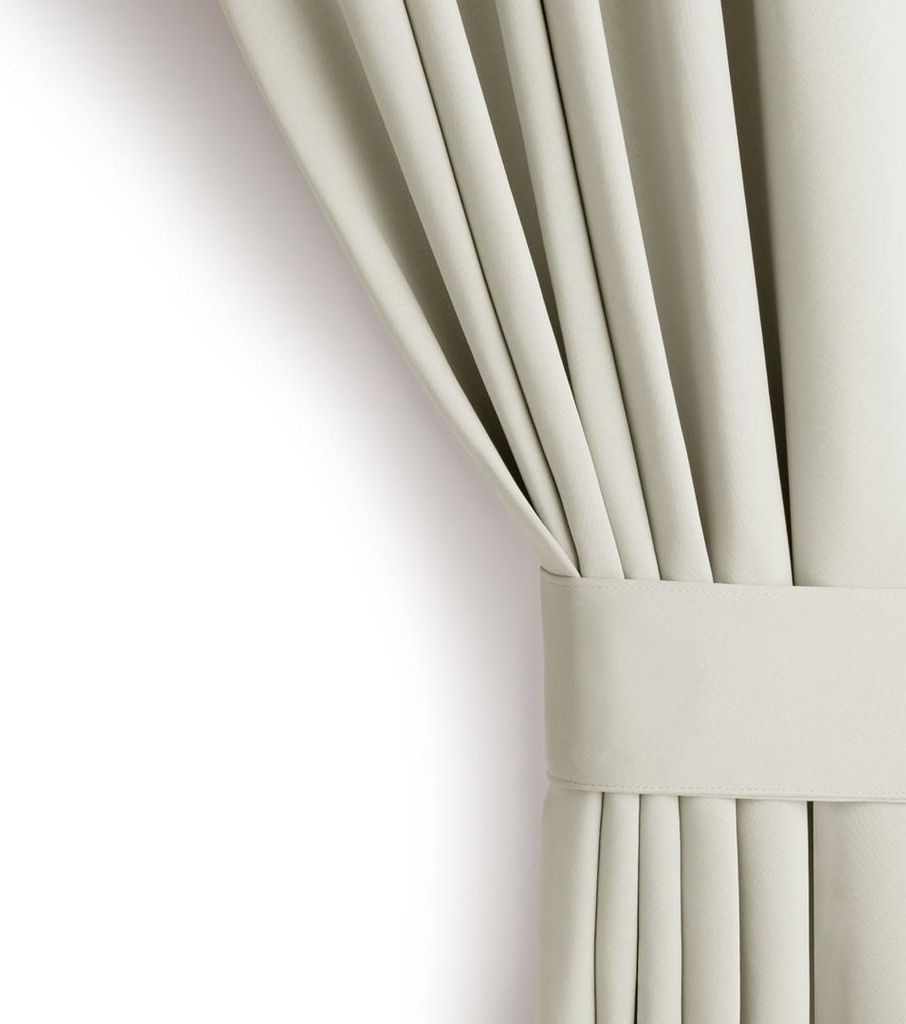 A close-up view of a cream-colored curtain with a tie-back.