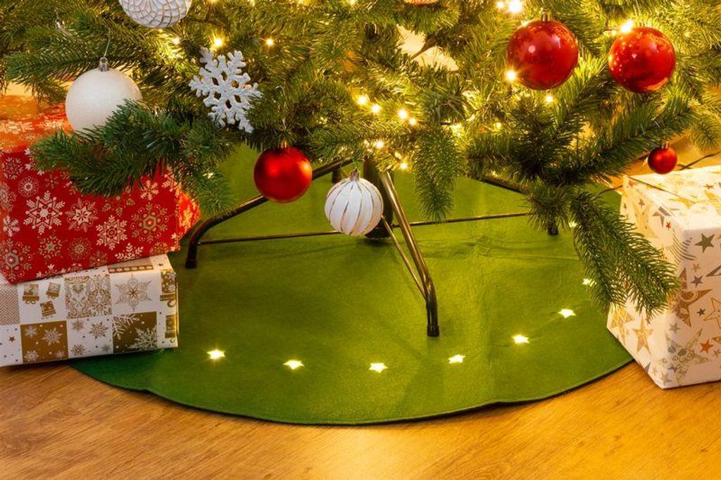 A Christmas tree skirt with embedded lights and gifts underneath.