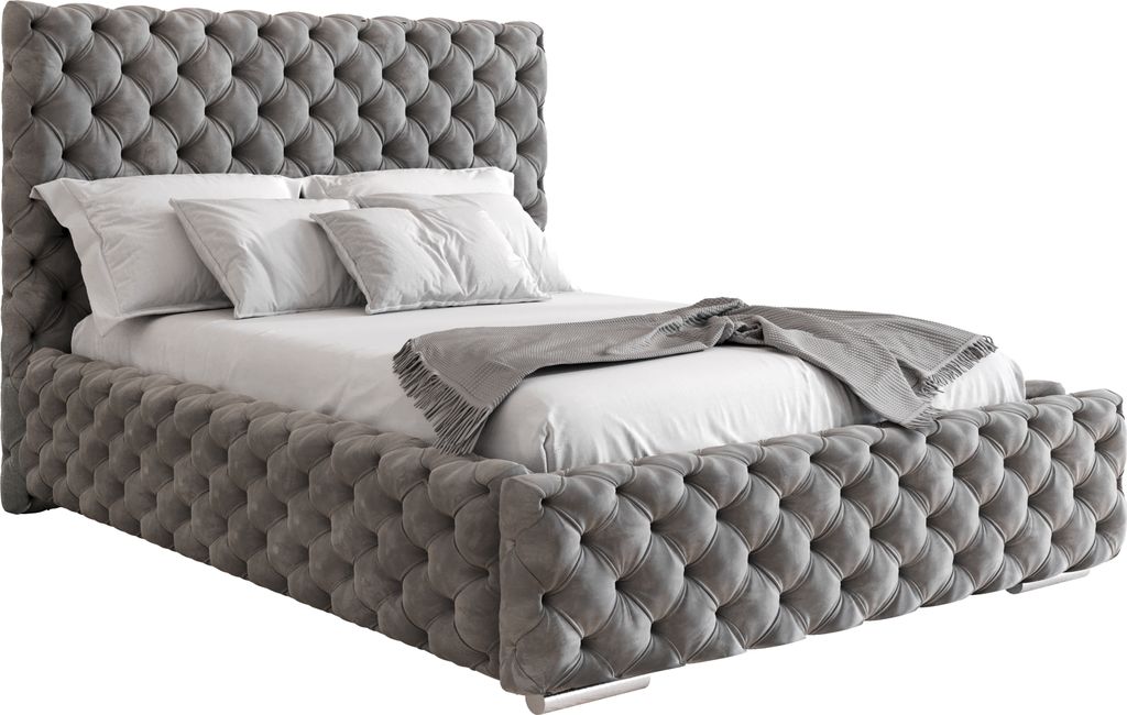 A tufted upholstered bed with pillows and a blanket.