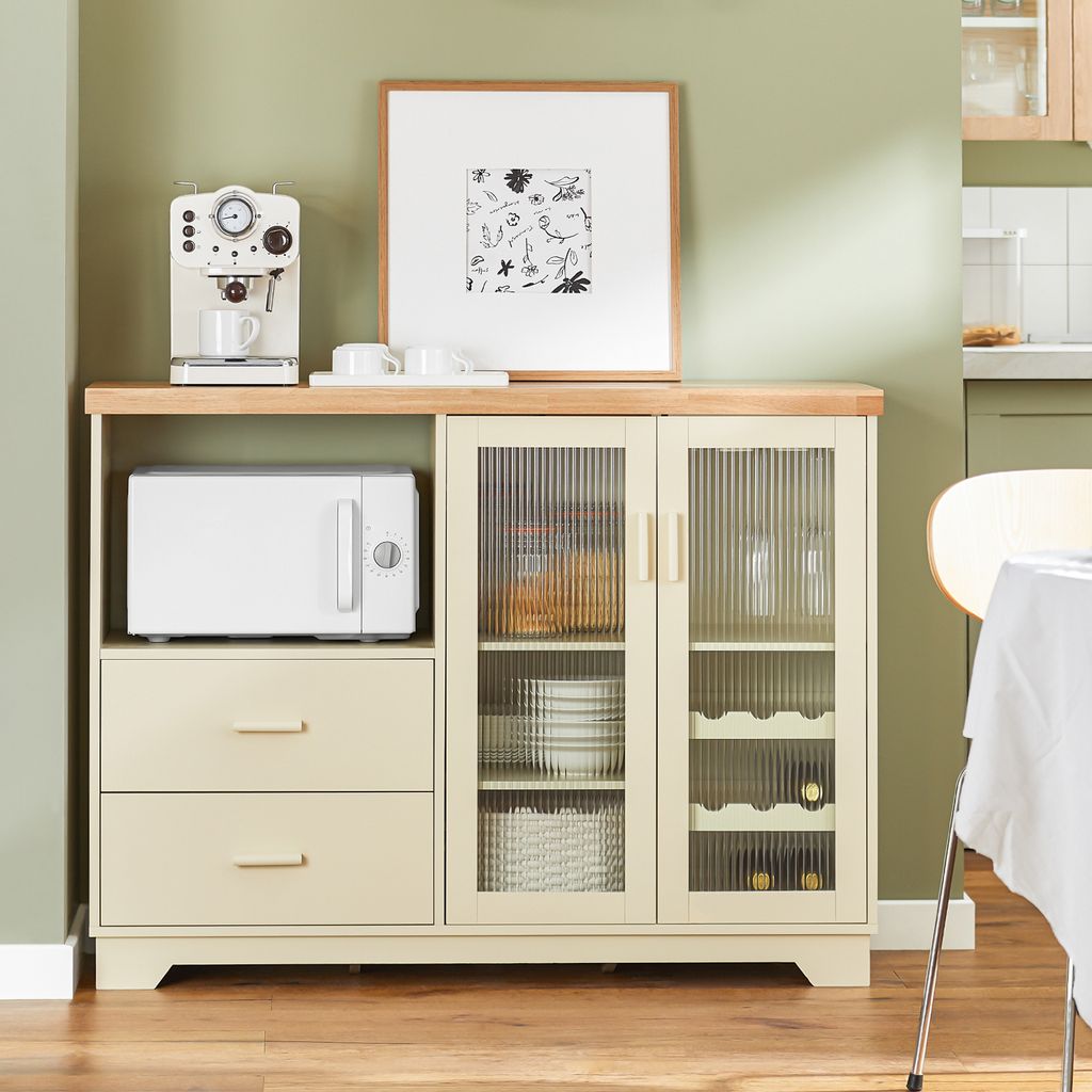 A kitchen or dining room sideboard with a microwave, coffee maker, and artwork on top.