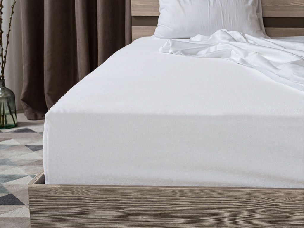 A white fitted sheet is shown on a bed with a wooden frame.