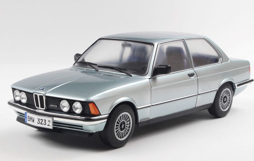 A silver and blue BMW 323I E21 1980 model car is shown from a three-quarter front angle against a white background.