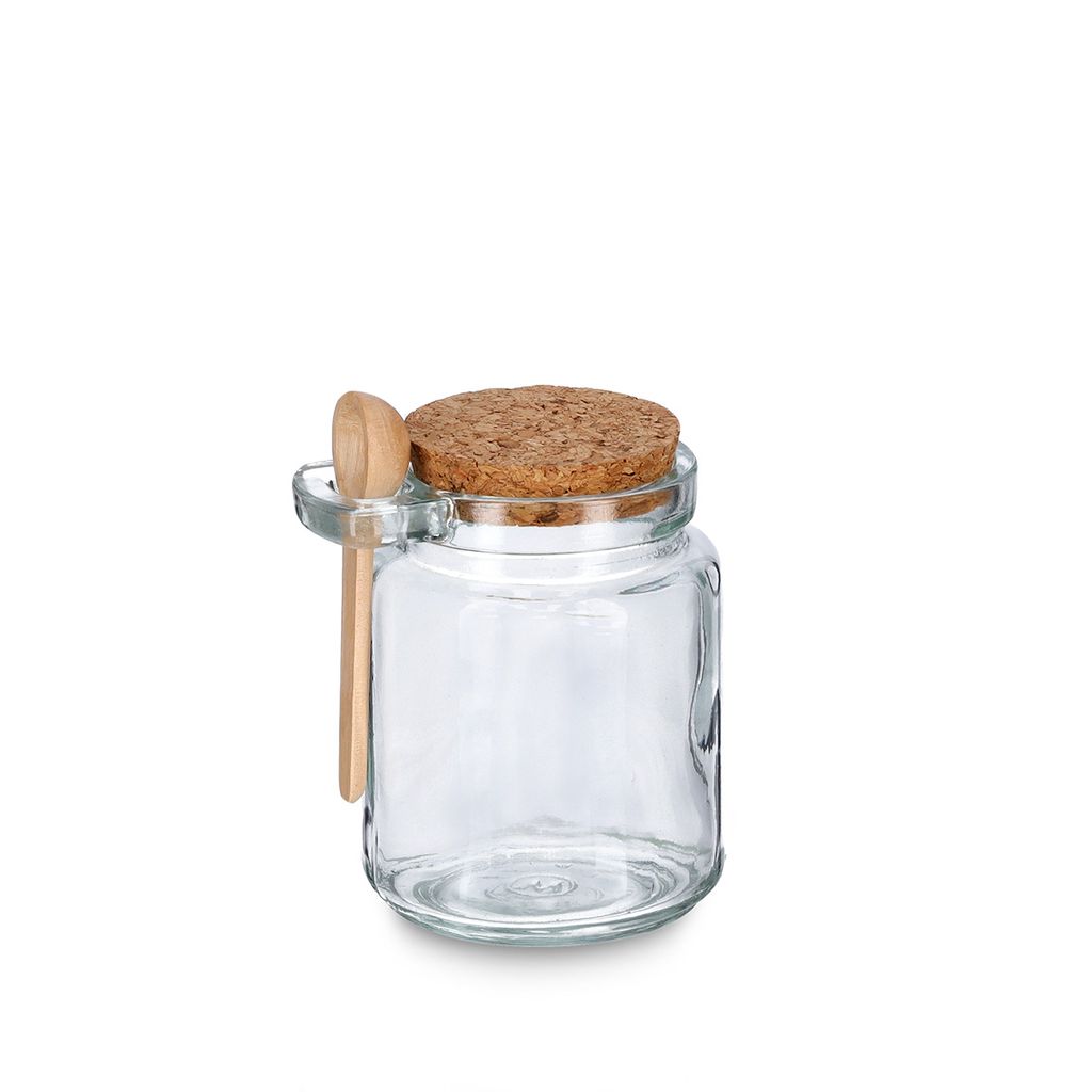 A clear glass jar with a cork lid and a small wooden spoon attached to the side.