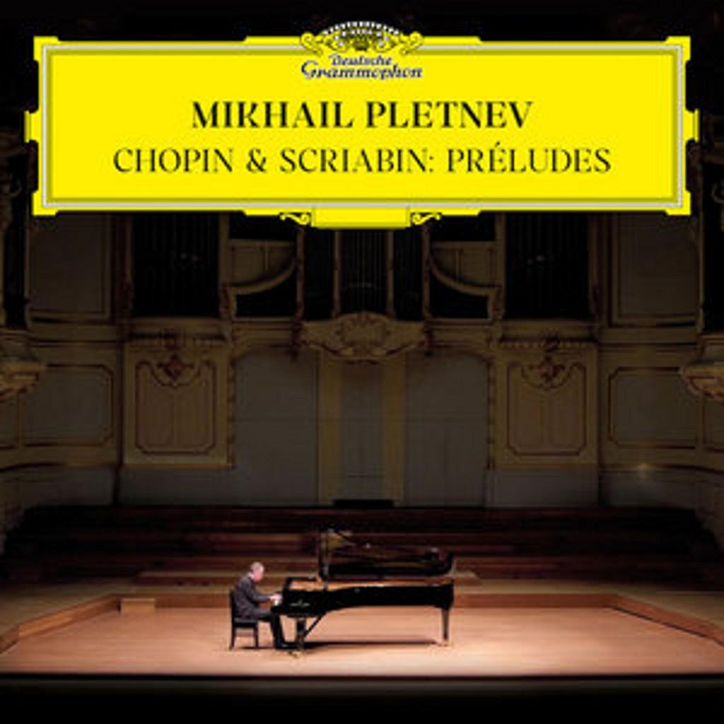 A pianist performs on a grand piano on a stage in a concert hall.