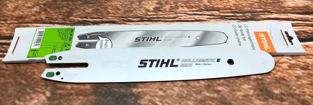 Two STIHL chainsaw guide bars are displayed on a wooden surface, one in its packaging.