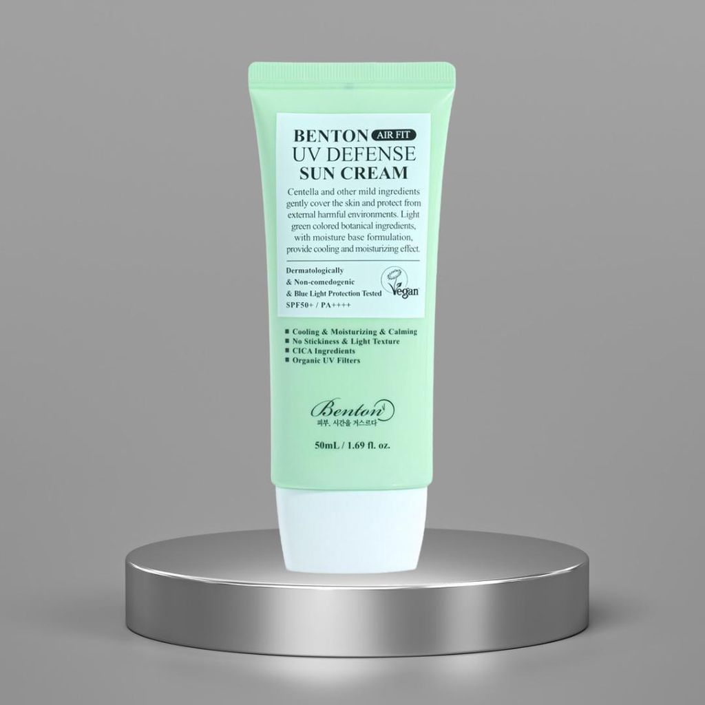 A green tube of sunscreen sits on a silver pedestal against a gray background.