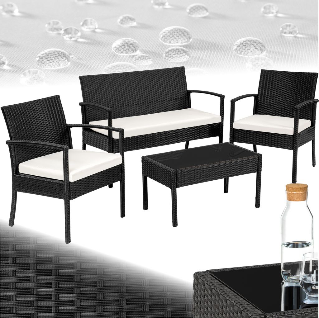 A black rattan furniture set with white cushions, including a loveseat, two chairs, and a coffee table, displayed on a white background with water droplets.