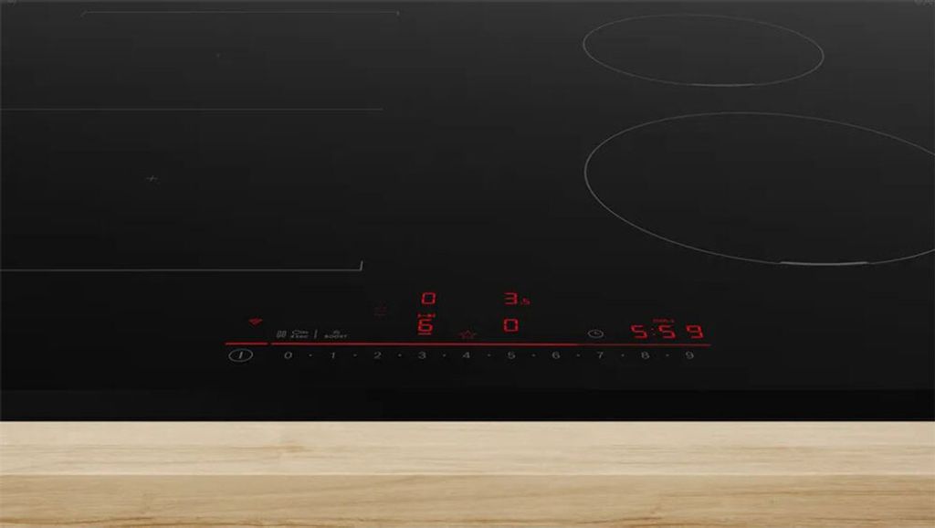 A close-up shot of a black induction cooktop with red digital displays.