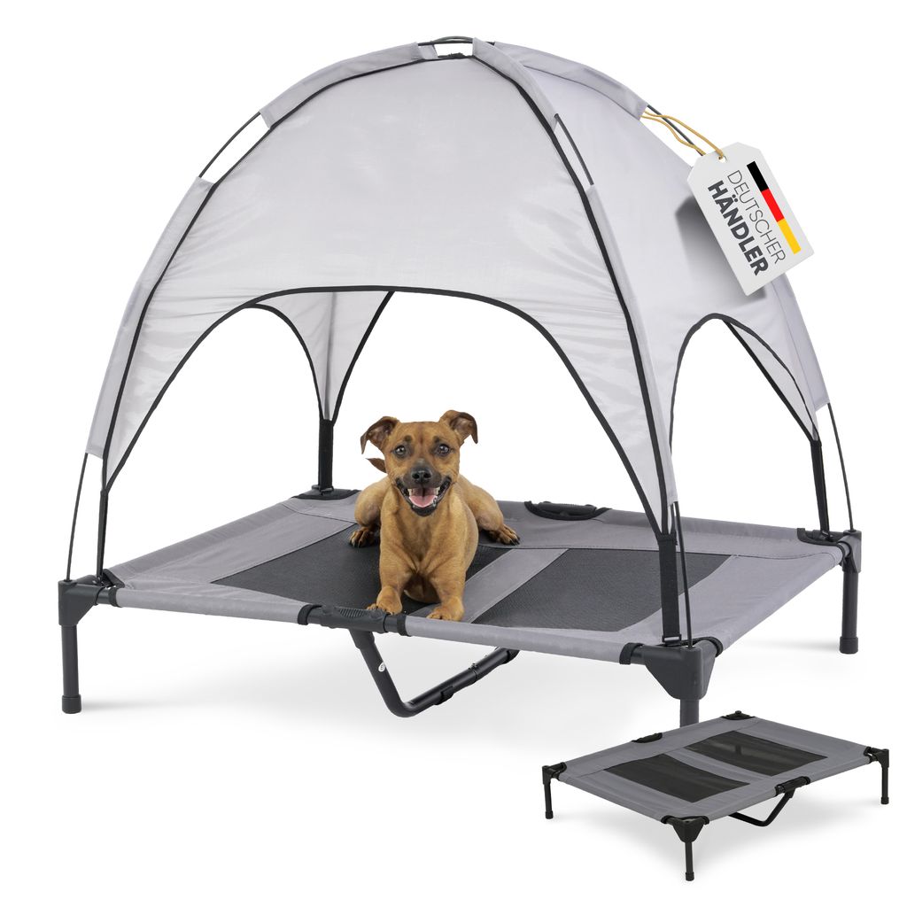 A dog is lying on a raised dog bed with a canopy.