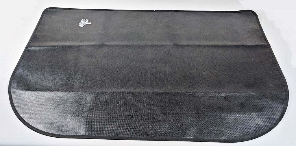 A black fire-resistant mat is laid flat on a white surface.