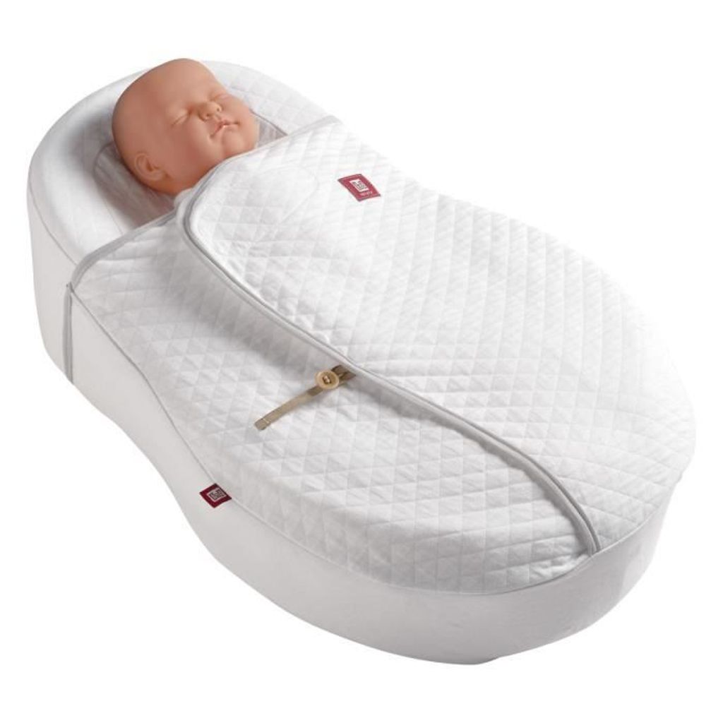 A baby doll is lying in a white baby cocoon or sleeping bag.