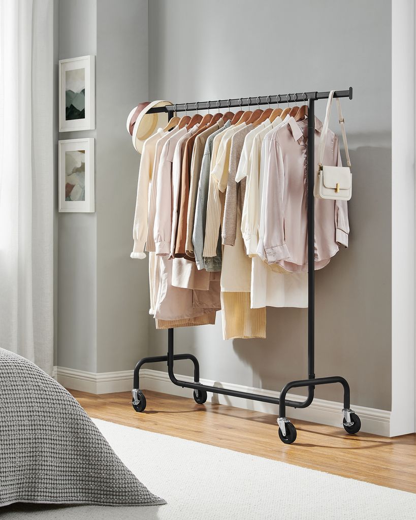 A clothing rack filled with pastel-colored women's clothing stands in a well-lit room.