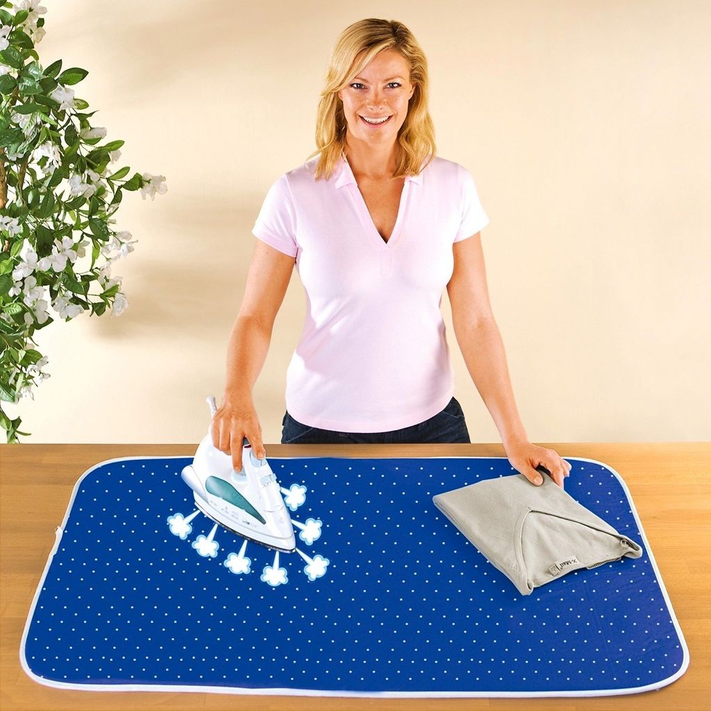 A woman is ironing a shirt on a portable ironing mat.