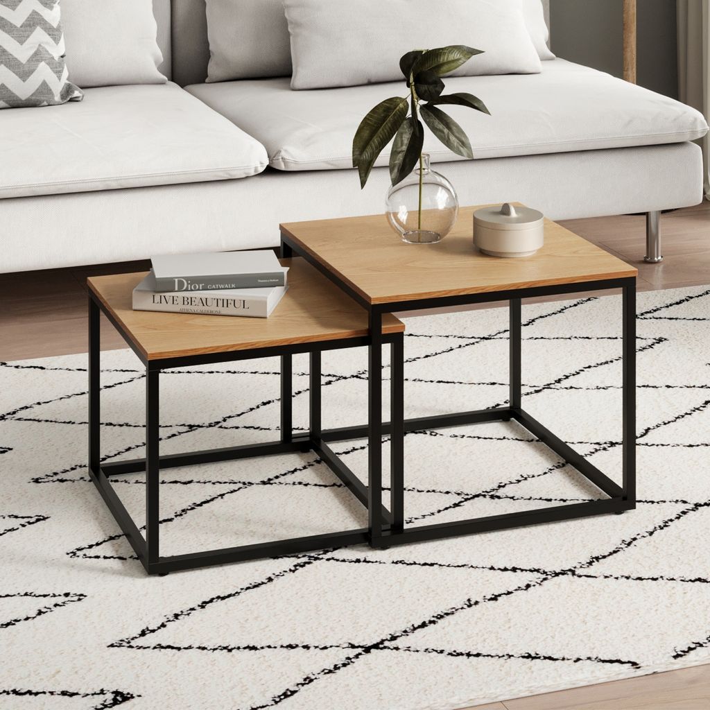 A living room scene with a couch, rug, and nesting coffee tables.